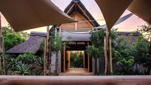 A wooden structure with a thatched roof, surrounded by greenery and a clear sky. - Royal Thonga Safari Lodge (uMhlabuyalingana)