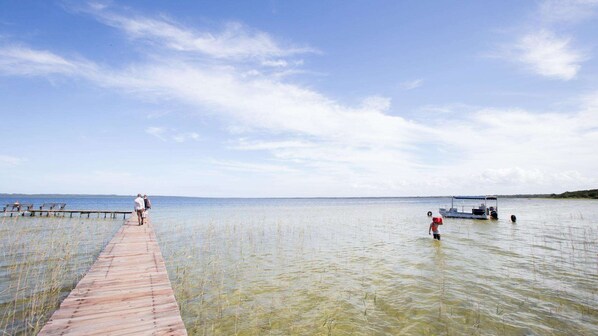 Un muelle de madera que se adentra en una masa de agua tranquila bajo un cielo despejado.