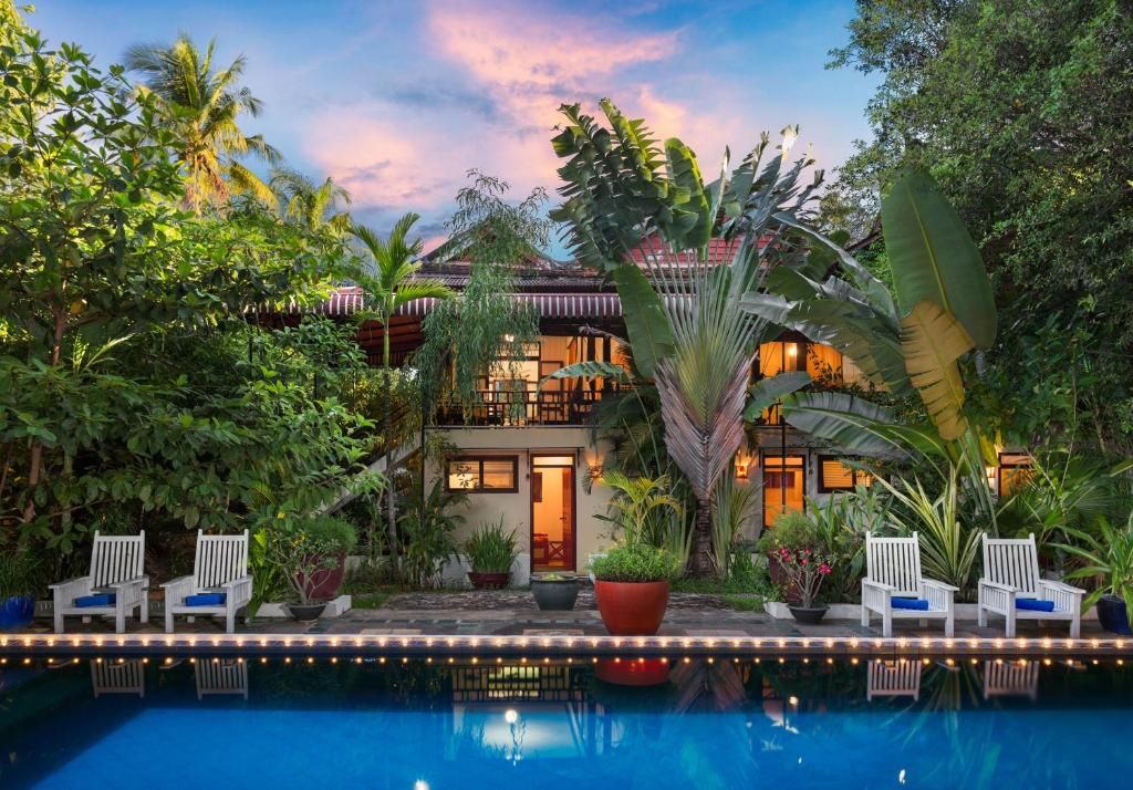 A poolside area with lounge chairs, a pool, and a building with a traditional architectural style.