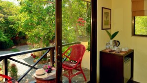 A balcony with a red chair, a wicker basket, and a small table with a hat and a vase. - The Cockatoo Nature Resort & Spa (Siem Reap)
