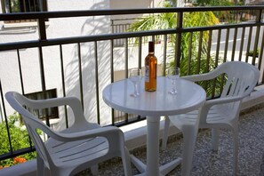 A round table with two chairs on a balcony, a bottle of wine, and two glasses.