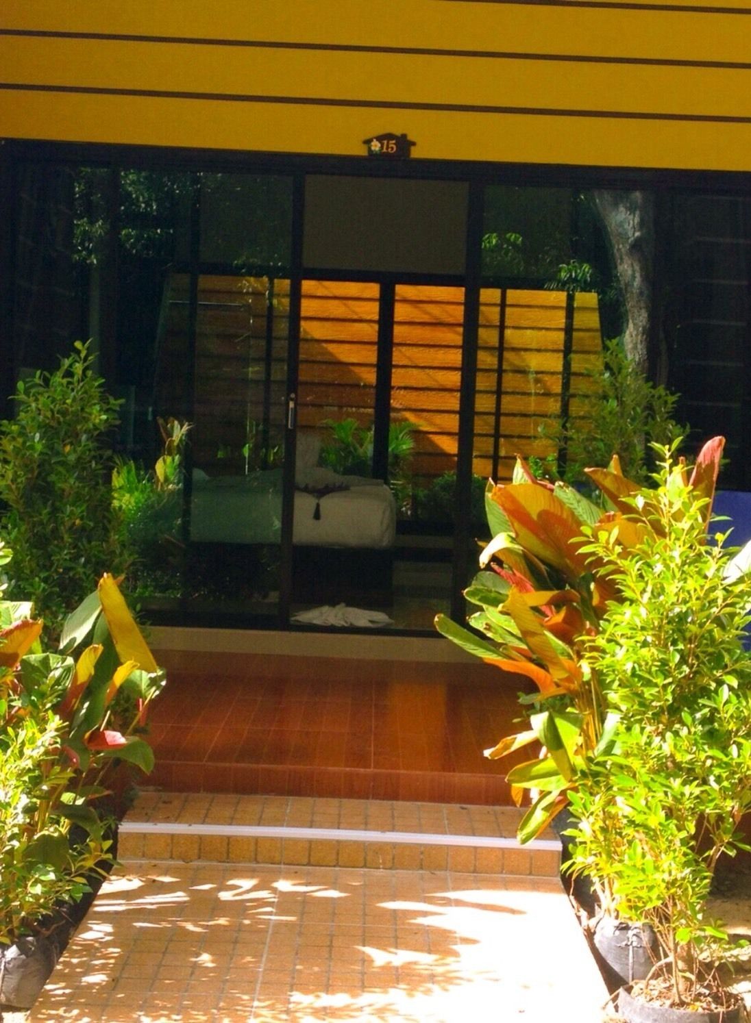 A building entrance with a tiled floor, potted plants, and a wooden fence.