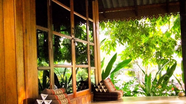 Una habitación con ventanas amplias, suelo de madera y un sofá tradicional con cojines.