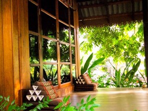 A room with large windows, wooden flooring, and a traditional sofa with cushions. - Lipe Sunset Forest Resort (Koh Lipe)