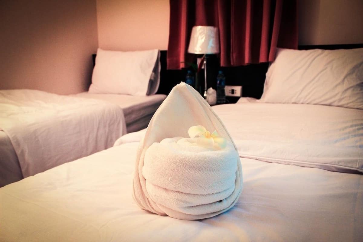 A hotel room with two beds, each with white linens, and a towel placed on the bed in the foreground.