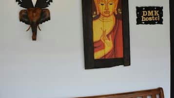 A wooden bench, a wall-mounted lamp with wings, and a framed Buddha painting.