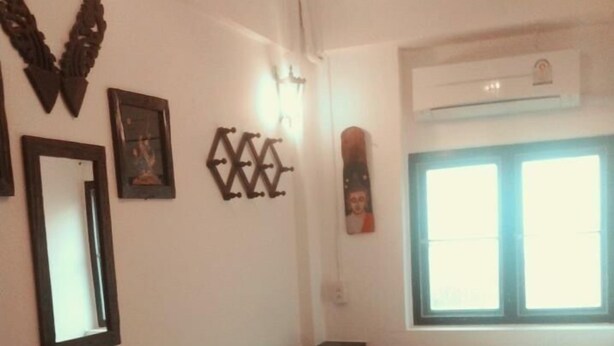 A room with a bed, a desk, and a chair. There is a window with blinds, a ceiling fan, and wall decorations. - DMK Hostel Donmueang Airport (Bangkok)