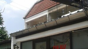 A building with a sign that reads "DMK HOSTEL" and a large glass door with the same name. - DMK Hostel Donmueang Airport (Bangkok)