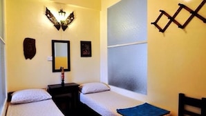 A small room with two single beds, a nightstand, a mirror, and decorative wall art. - DMK Hostel Donmueang Airport (Bangkok)