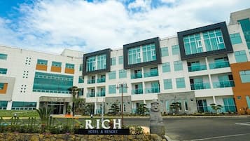 Een modern hotel met een bord waarop 'RICH HOTEL & RESORT' staat.