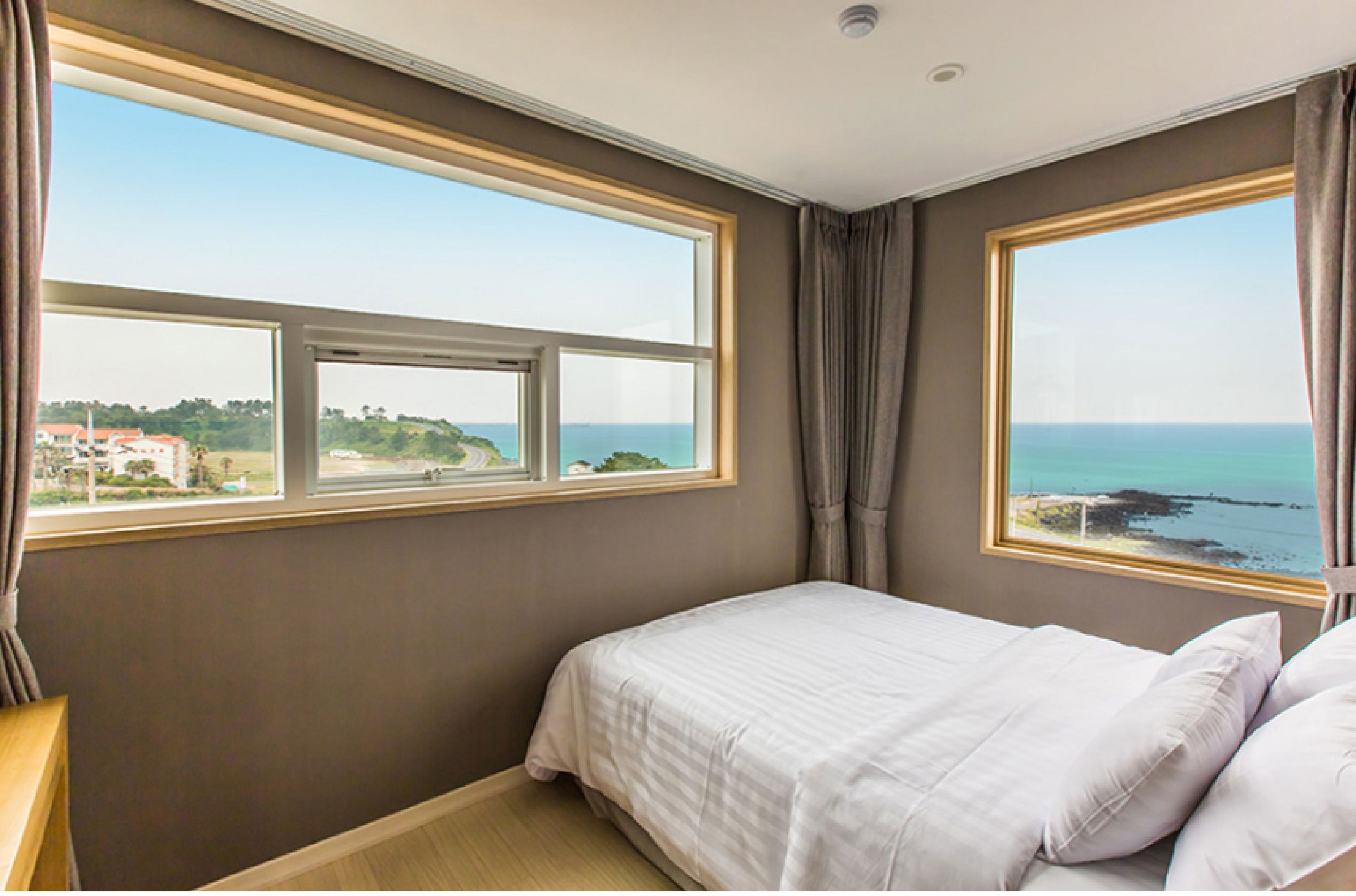 Une chambre dotée d’une grande fenêtre donnant sur la mer et sur une côte lointaine.