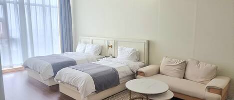 A hotel room with two beds, a sofa, and a small round table.