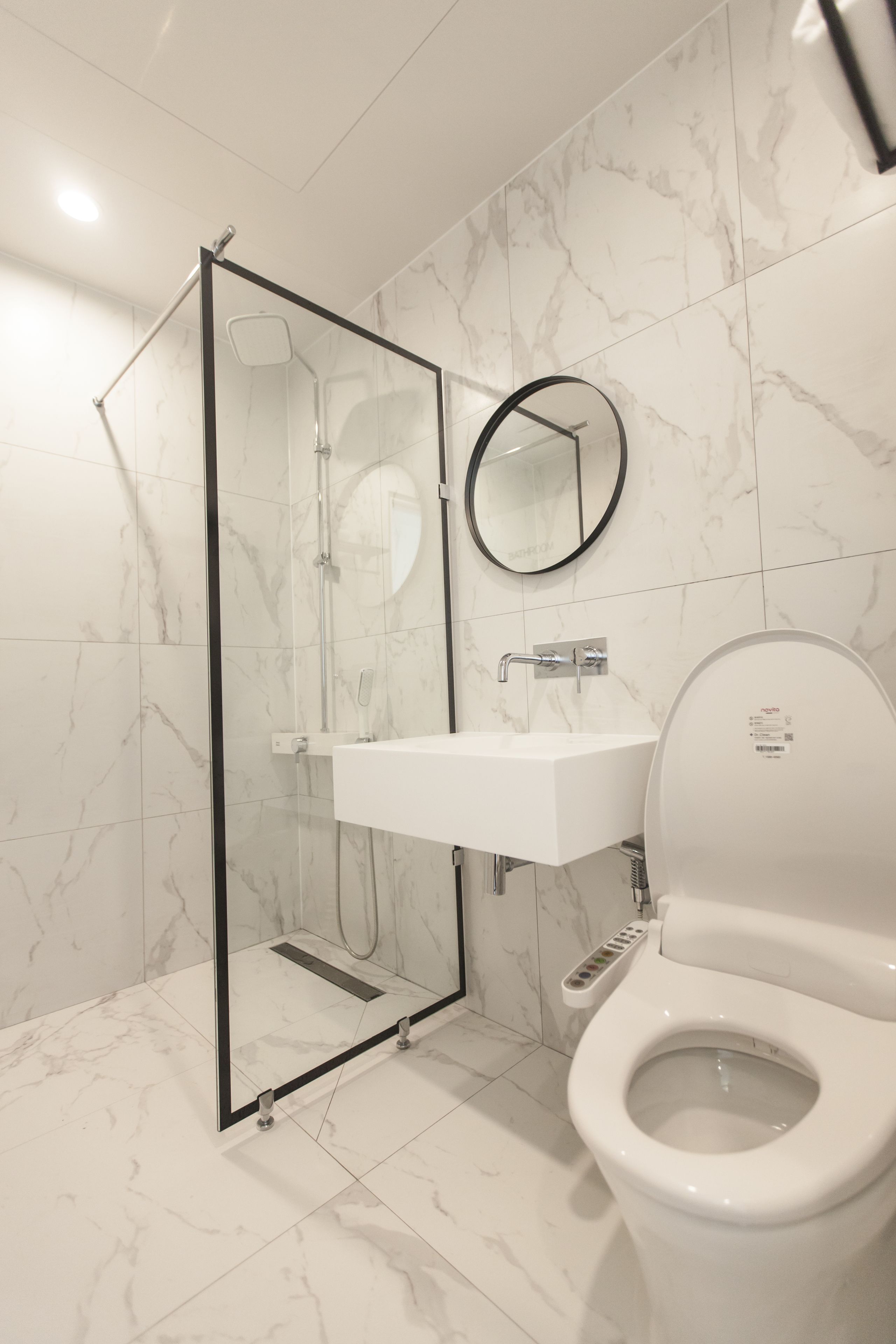 Une salle de bain moderne avec une douche à parois de verre, un lavabo blanc et des toilettes.