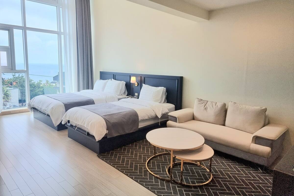 Een hotelkamer met twee bedden, een bank en een klein rond tafeltje.