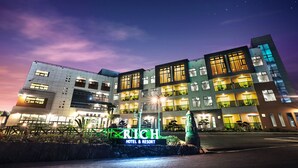 Een meerlaags hotel met een modern ontwerp, met een opvallende entree en verlichte signage.