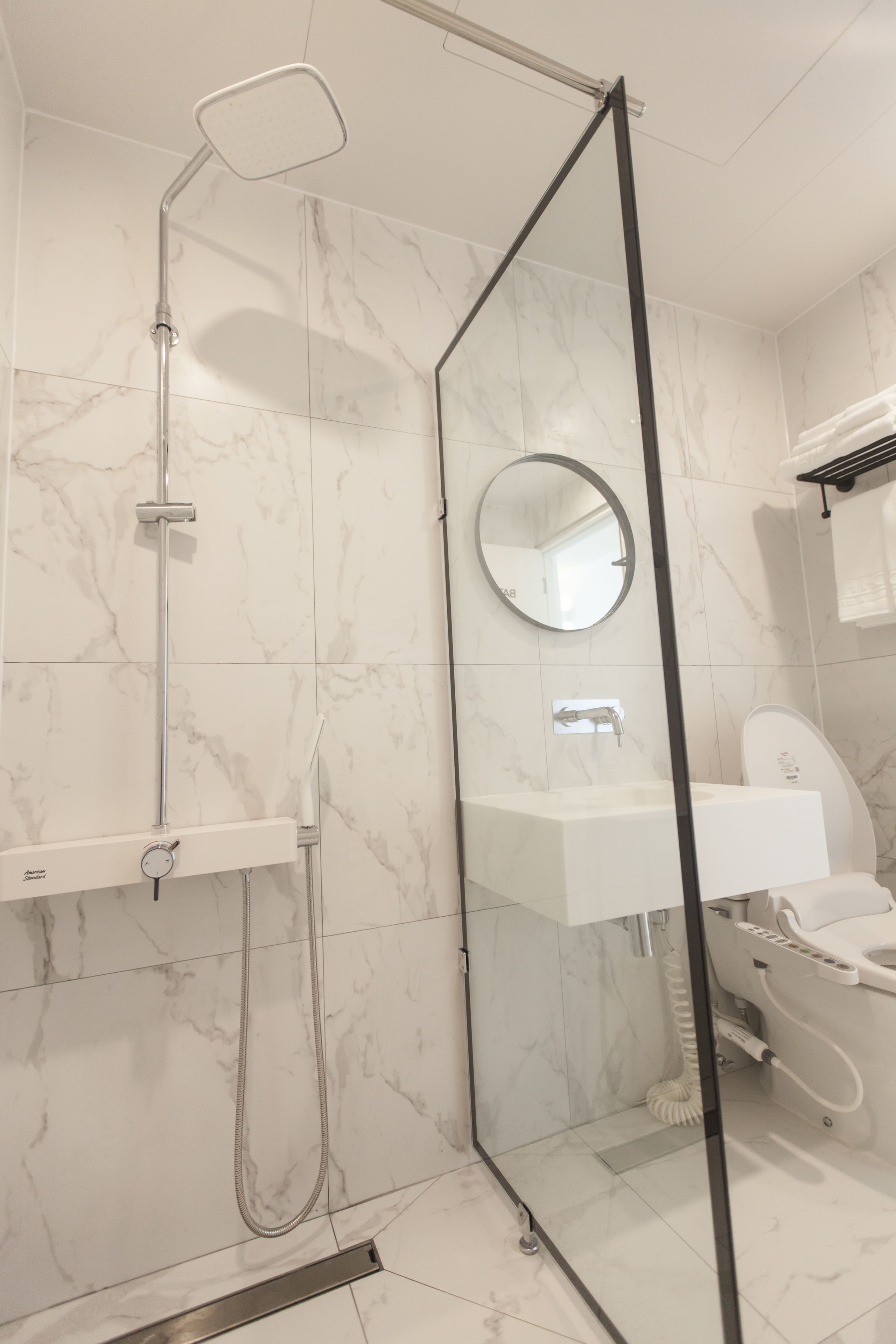 Un baño moderno con cabina de ducha de vidrio, un lavamanos blanco y un espejo.