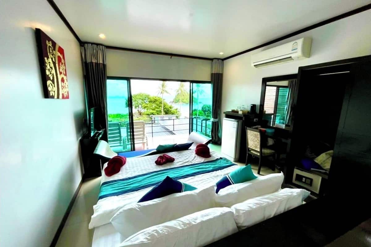 A hotel room with two beds, a desk, and a large window with a view of the outdoors.