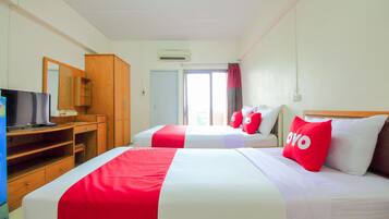 A hotel room with two beds, a TV, a wooden wardrobe, and a door leading to a balcony.