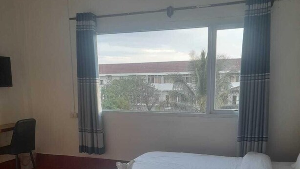 Una habitación de hotel con cama, escritorio y ventana con cortinas.