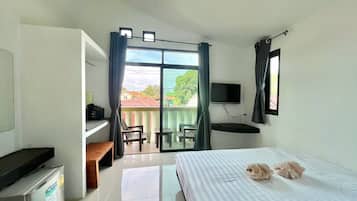 A hotel room with a bed, a desk, a television, and a view of the outside.