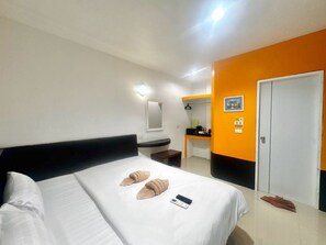 A hotel room with a bed, a desk, a mirror, and a door. - Harmony Bed and Bakery (Koh Lipe)