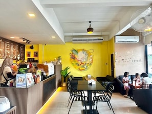 A cafe interior with a counter, seating area, and a mural on the wall. - Harmony Bed and Bakery (Koh Lipe)