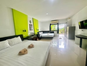 A hotel room with two beds, a desk, a TV, and a window with a view. - Harmony Bed and Bakery (Koh Lipe)