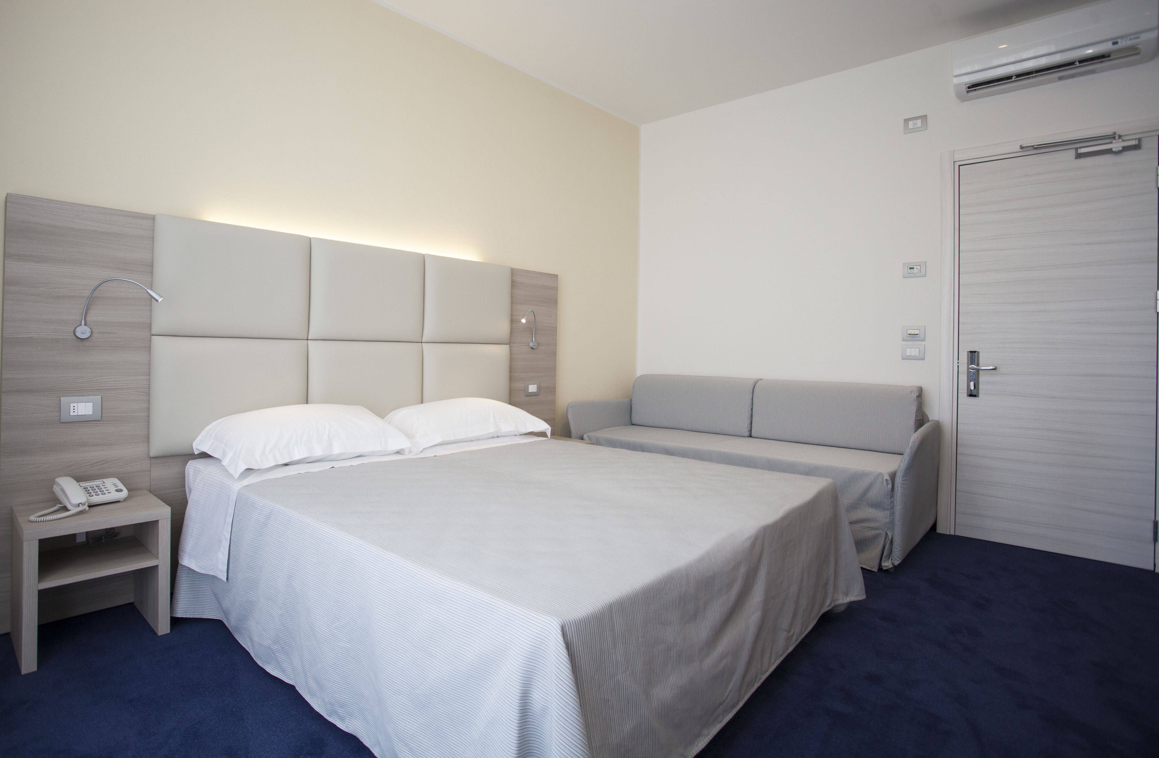Een moderne hotelkamer met een groot bed, nachtkastjes, een inloopdouche en een kledingkast.