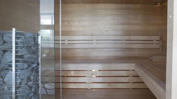 A modern spa room with wooden benches and a stone wall. - Hotel Bella Lazise (Lazise)