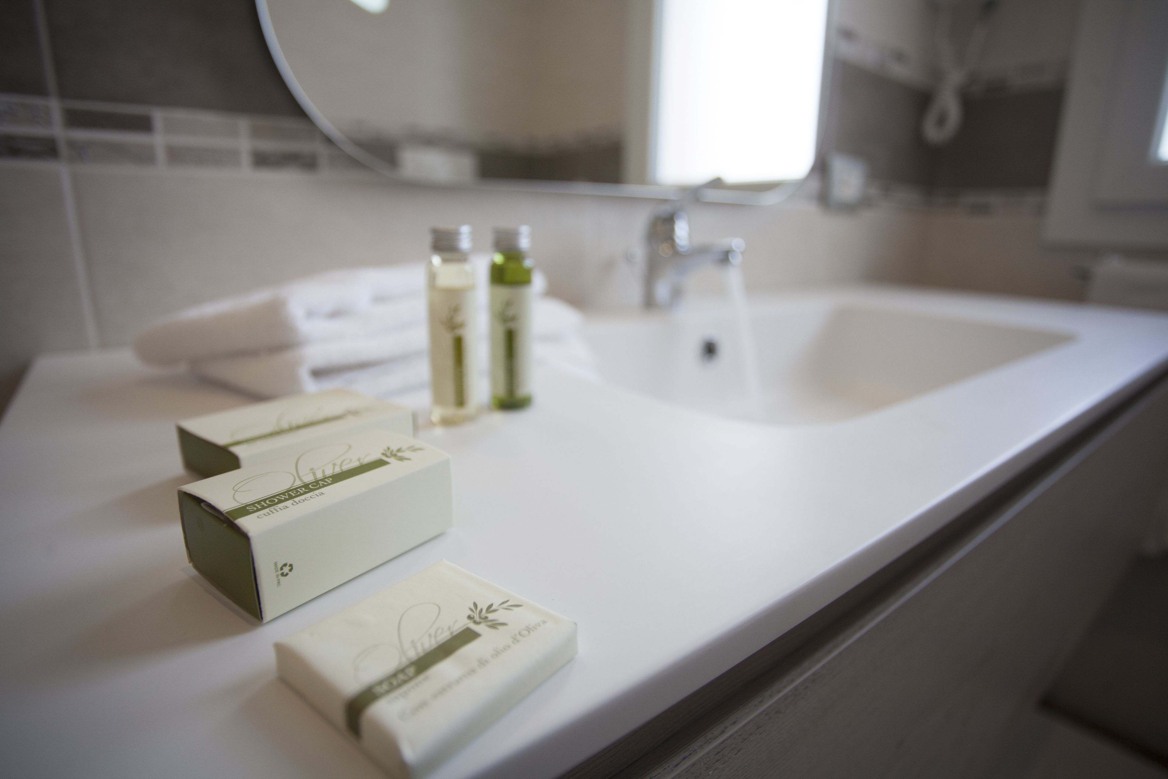 A bathroom with a white sink, two bottles of liquid soap, and a towel on the counter.