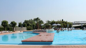 A swimming pool with a wooden deck, lounge chairs, and umbrellas. - Hotel Bella Lazise (Lazise)