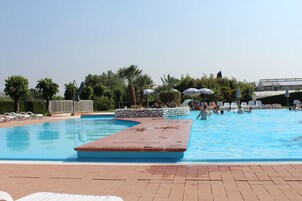 Una piscina al aire libre, sombrillas, sillones reclinables de piscina