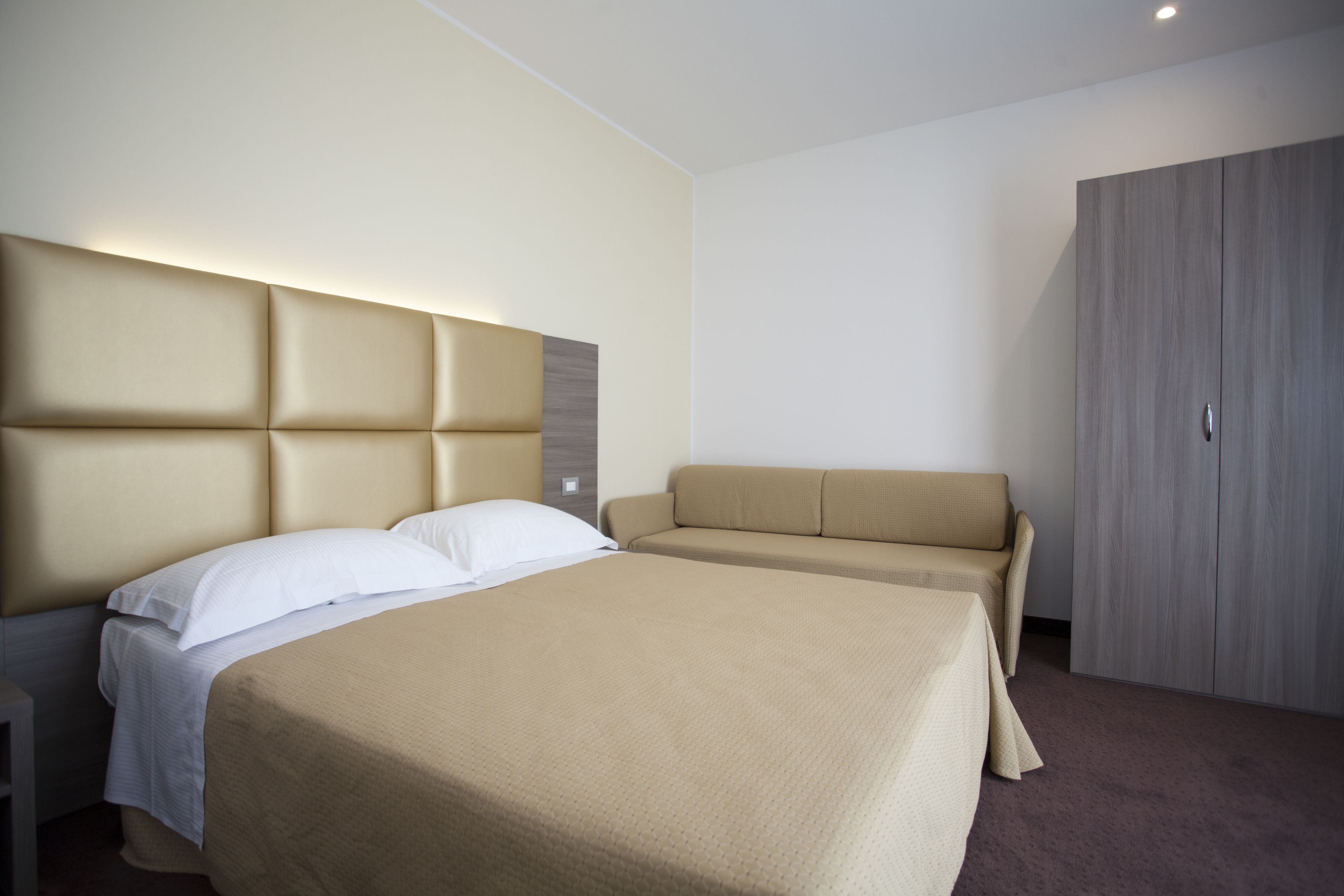 Une chambre d’hôtel avec un grand lit, un canapé, une armoire et une table de chevet.