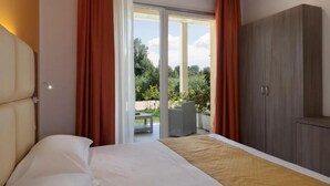 A hotel room with a bed, a wardrobe, and a sliding glass door leading to an outdoor area with a table and chairs. - Hotel Bella Lazise (Lazise)