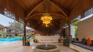 Un pabellón de madera con piscina, mostrador de recepción y una fuente.