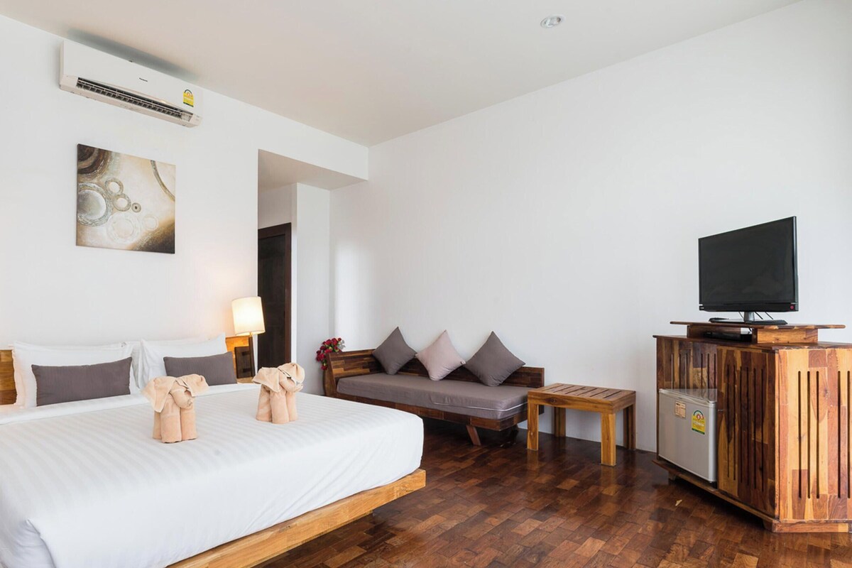 Una habitación de hotel con una cama de madera, lámparas de noche, un televisor, un armario de madera y un cuadro en la pared.