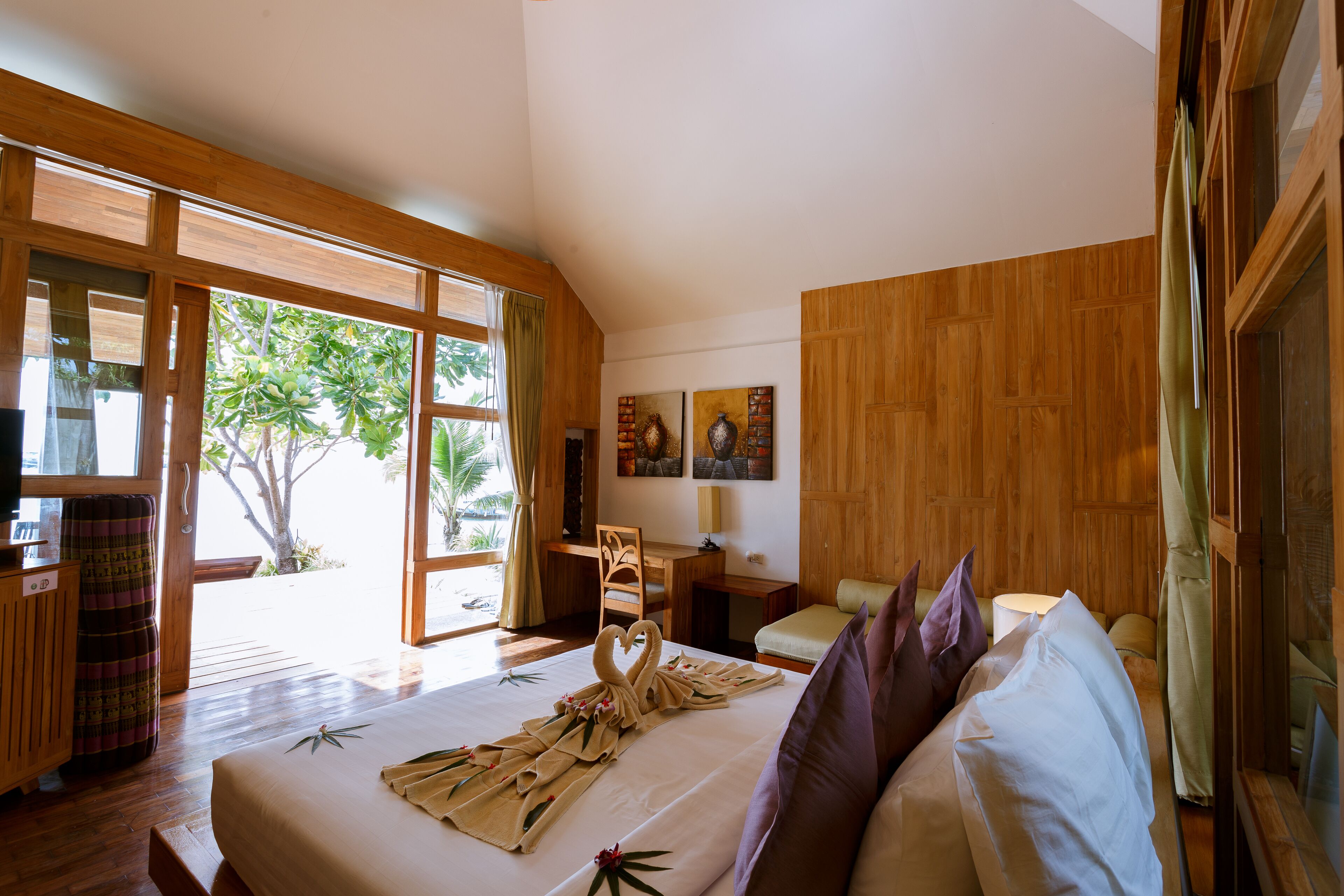 A spacious room with a large bed, wooden furniture, and a view of the outdoors.