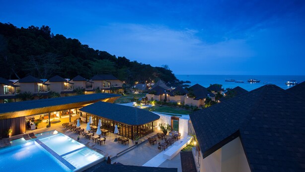 Un resort con varias edificaciones tipo bungalow, una piscina y vista al océano.