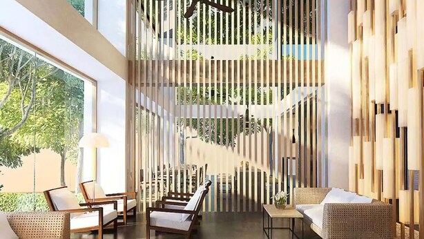 A modern interior with a high ceiling, a central staircase, and seating areas with wicker furniture.
