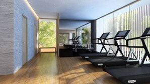 A modern gym with treadmills, a wooden floor, large windows, and a view of greenery.
