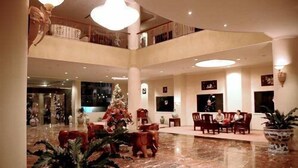 A spacious lobby with a high ceiling, marble flooring, and a Christmas tree. - Hotel Grand Tiga Mustika (Balikpapan)
