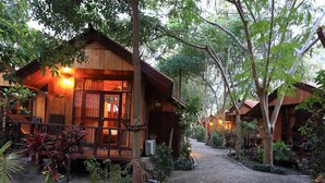 A wooden lodge with a paved pathway, surrounded by lush greenery and potted plants. - Bundhaya Resort Koh Lipe (Koh Lipe)