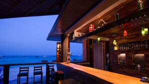 A bar with a view of the sea, wooden furniture, and bottles on shelves. - Bundhaya Resort Koh Lipe (Koh Lipe)