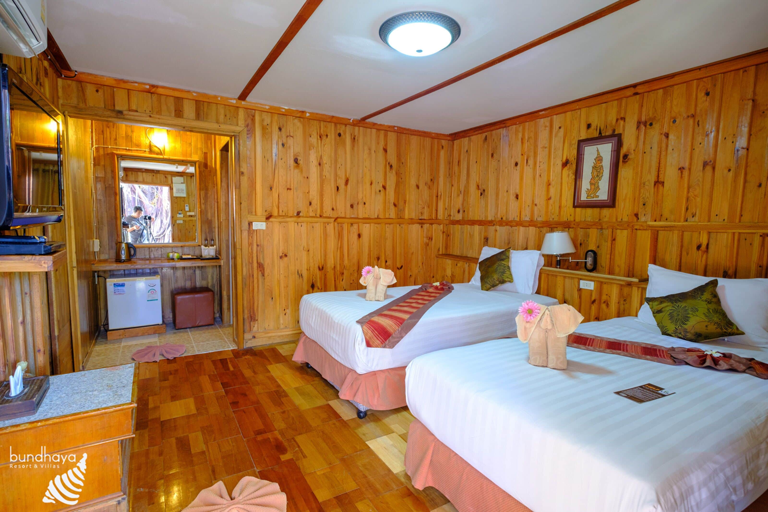 A wooden room with two beds, a small desk, and a mirror.