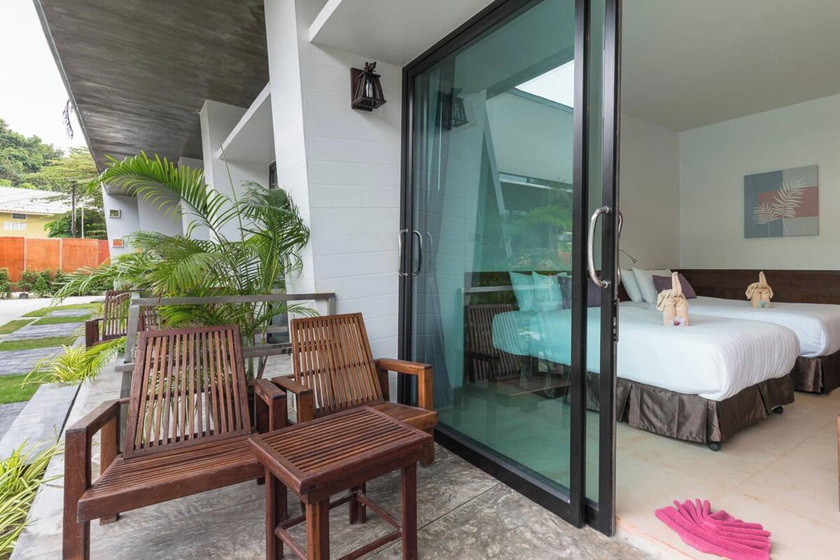 Een kamer met een bed, een glazen deur naar een balkon en een zithoek met houten meubels.