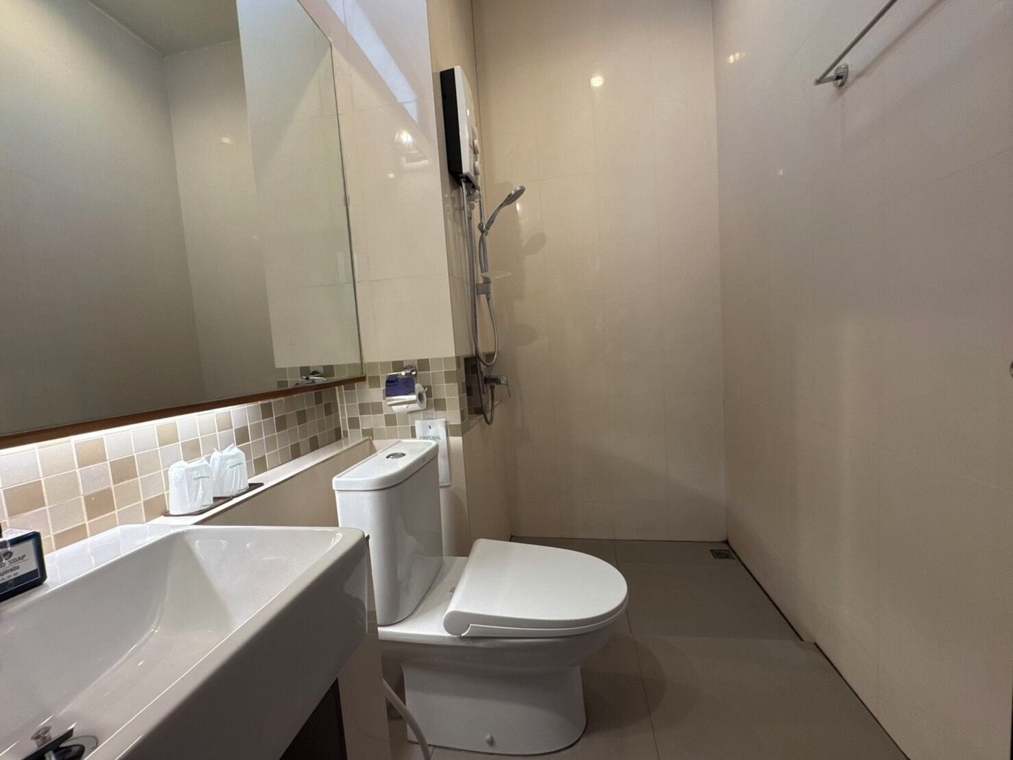 Un baño moderno con inodoro blanco, lavabo y ducha.