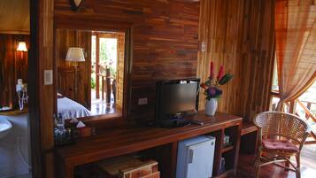 A wooden interior with a television, a small refrigerator, a chair, and a mirror.