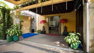 A hotel entrance with a covered porch, potted plants, and a statue.