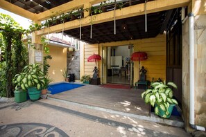 Een hotelingang met een overdekte veranda, potplanten en een standbeeld.