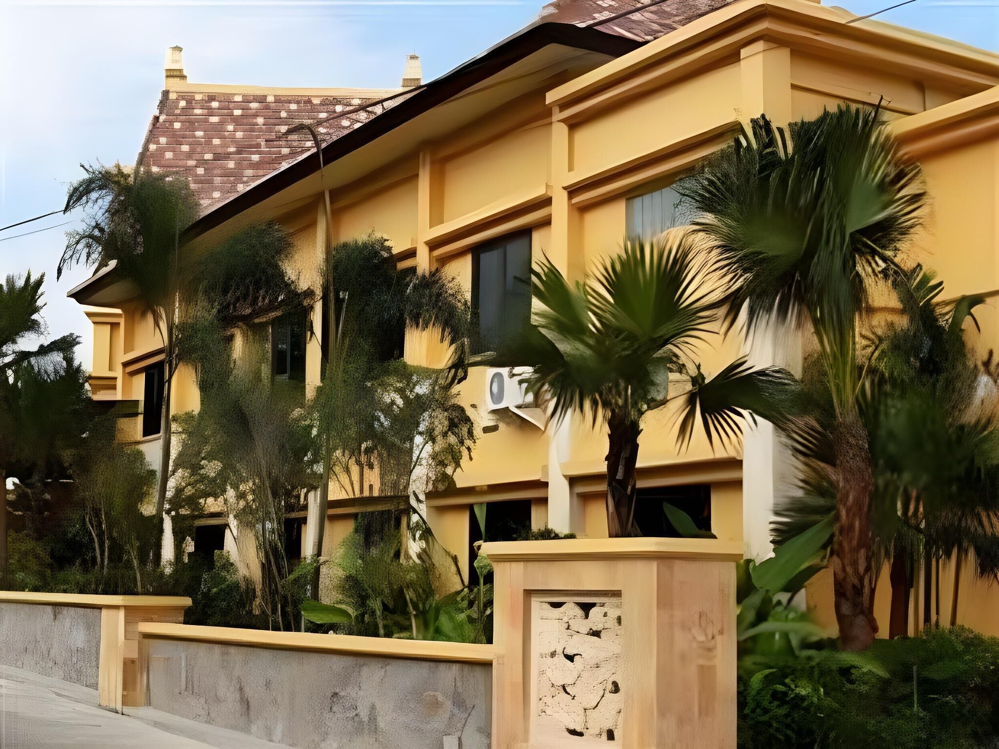 A multi-story building with a yellow facade, large windows, and a tiled roof.